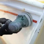 Image of a worker cleaning the hull of a boat, preventable by using high quality boat lift accessories