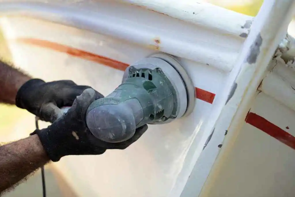 Image of a worker cleaning the hull of a boat, preventable by using high quality boat lift accessories